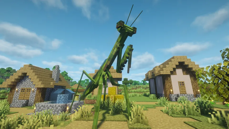 マインクラフトの村の前に現れた、ArPhEx Modの巨大なカマキリ（Mantis）。村の家屋よりも巨大な体躯で、鮮やかな緑色をしており、鎌のような前脚を立てて草むらに立っている。青空を背景にした、クリーチャーの巨大さが際立つスクリーンショット。