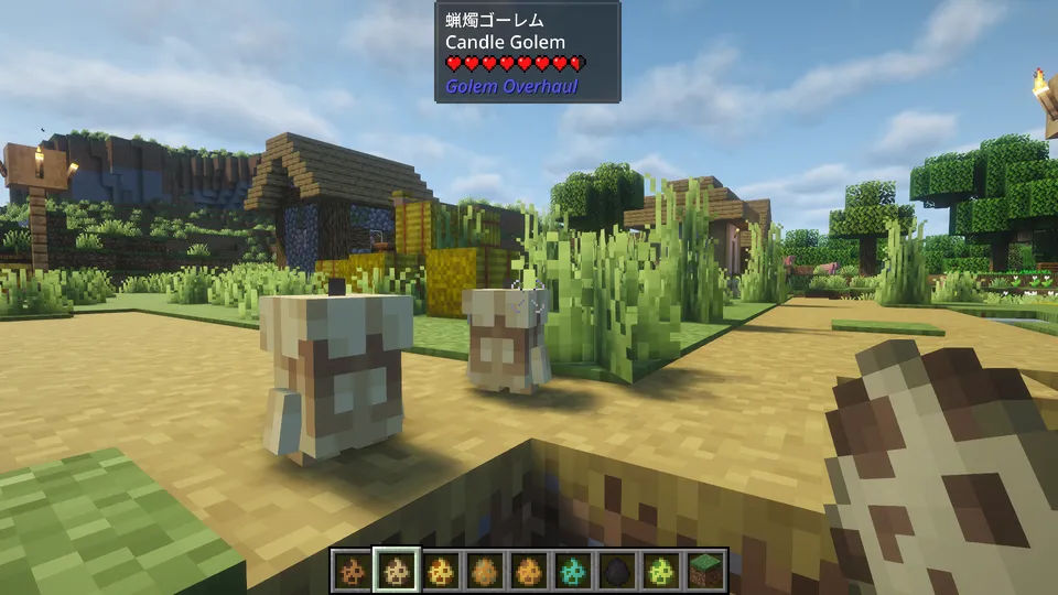 Golem Overhaul Modの「蝋燭ゴーレム」。白と茶色のツートンカラーで、頭に芯のような突起がある、溶けかかったキャンドルのような姿。村の道をトコトコと歩く、小さく幻想的なクリーチャー。