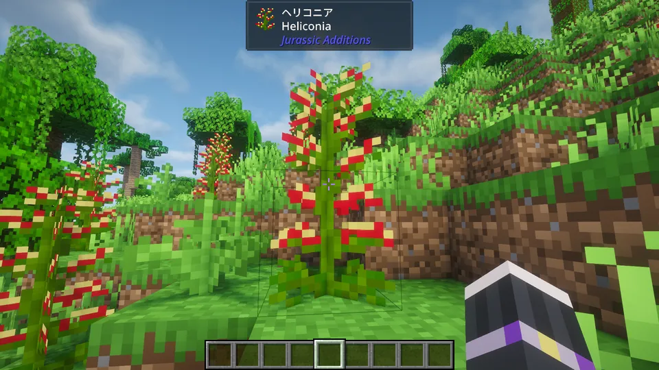 Jurassic Additions Modで追加される植物「ヘリコニア」。ジャングルバイオームの崖際に咲く、赤と黄色の鮮やかな色合いをした背の高い古代植物。緑豊かな熱帯の風景に彩りを添えている。
