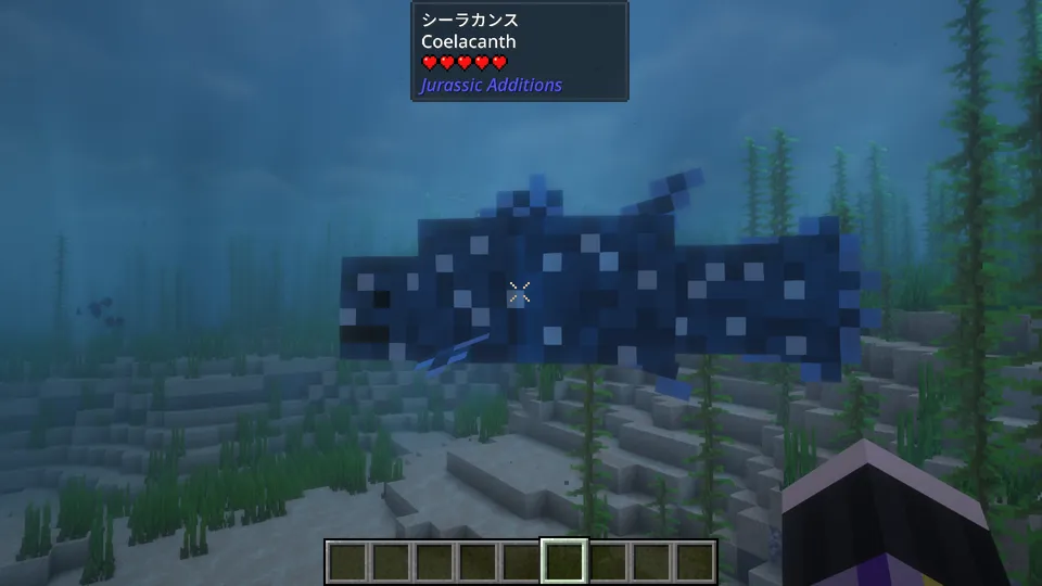 Jurassic Additions Modの「シーラカンス」。深い青色の体に白い斑点模様がある古代魚。日光が差し込む穏やかな海底の海藻の間を悠々と泳いでいる様子。画面上部にはMod独自のUIで名前と体力が表示されている。