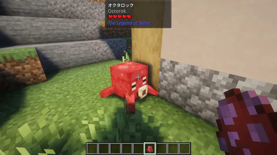 The Legend of Steve Modに登場する敵モブ「オクタロック（Octorok）」。赤いタコのような姿をしており、口から岩を吐き出して攻撃してくる。村の建物付近の草地に佇んでいる様子。画面上部にはMod独自のUIで名前と体力が表示されている。